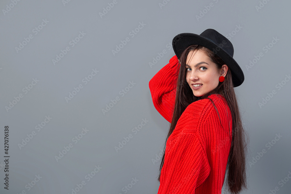 Wall mural young teenage female with elegant black hat and gloves, dressed in a red sweater, isolated on gray