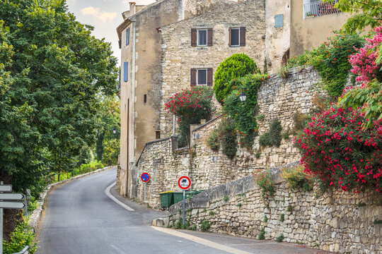 Empty picturesque road along the stone wall and old historical houses in Lacoste, Provence, France.