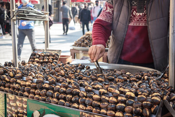 The street vendor is grilling the chestnuts.  Famous Bursa chestnut in Turkey.