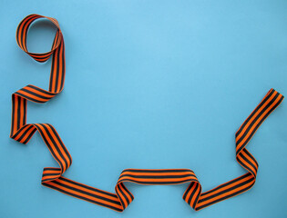Fototapeta premium 9th May. Holiday Victory Day. The St. George ribbon is spread around on a gray-blue background. View from above. Flat layout. Place for your text. 