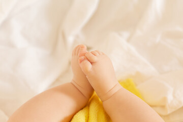Cute toddler lies in bed with yellow towel after bathing