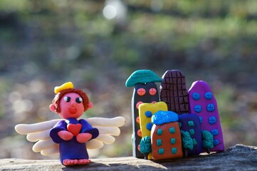 Angel figurine made of plasticine on a colored background.