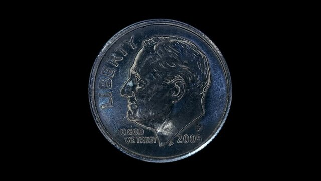 On a black background, one dime coin is glitters in the rays of light. Macro. Closeup