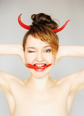 Funny girl portrait as a devil with the red chili peppers horns