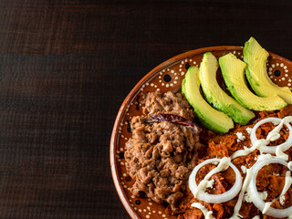 Chilaquiles con queso, cebolla aguacate y frijoles fritos.