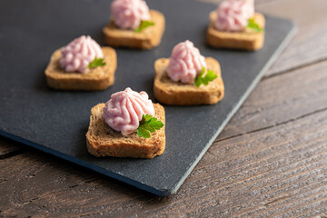 Crostini or canape with taramasalata on a slate board close-up