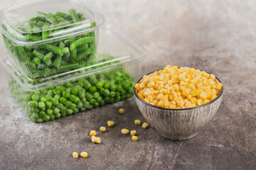 Plastic container with different organic deep frozen vegetables on a table