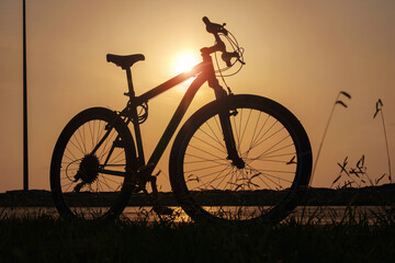 Fototapeta na wymiar Silhouette of a bike at sunset. The sun shines through the bicycle frame at the coast