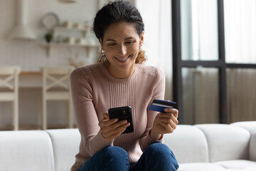 Safe mobile banking. Smiling latina lady client hold mobile phone credit bank card do online...