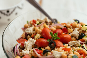 Home made mediterranean couscous salad with bell pepper, zucchini, tomatoes, chickpeas, olive and vegan feta