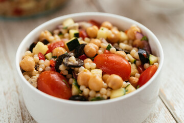 Home made mediterranean couscous salad with bell pepper, zucchini, tomatoes, chickpeas, olive and vegan feta