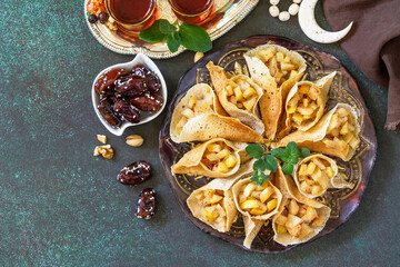 Arabic Cuisine. Ramadan Kareem Festive. Ramadan menu, arabian pancake katayef (katayev, qatayef) with apple filling and cinnamon. Top view flat lay. Copy space.