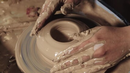Pottery crafting - woman's hands forms clay in the a pot shape smoothing the surface