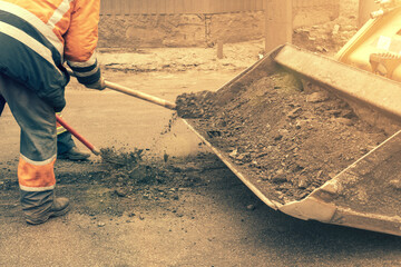 Traffic workers in bright orange reflective uniforms scrape off accumulated sand and debris between...