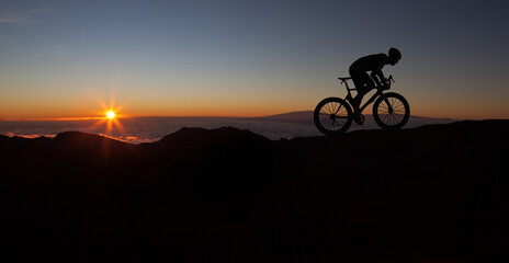 The silhouette of the cyclist on bike at sunset.A man ride on bike on the mountains. Sport and active life concept sunset time. A man riding a bicycle in a nature.