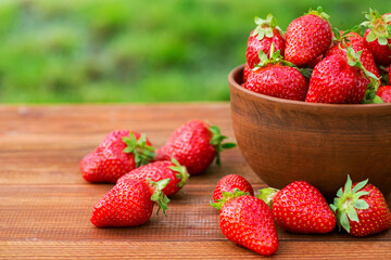Fresh juicy organic strawberries in a clay bowl. Ripe red strawberries in a bowl on a wooden table