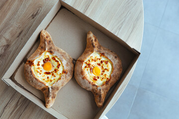 khachapuri in a cardboard box delivery an appetizing dish in Adjara with eggs and cheese