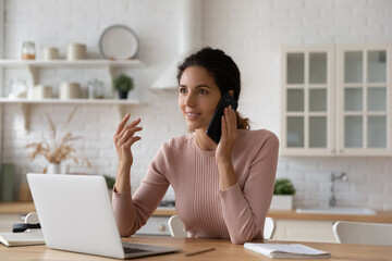 Inspired hispanic woman remote worker student sit by laptop calling teacher colleague to discuss...
