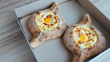 khachapuri in a cardboard box delivery an appetizing dish in Adjara with eggs and cheese