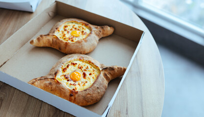 khachapuri in a cardboard box delivery an appetizing dish in Adjara with eggs and cheese