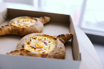 khachapuri in a cardboard box delivery an appetizing dish in Adjara with eggs and cheese