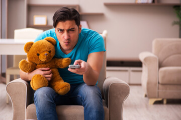 Young man sitting with bear toy at home