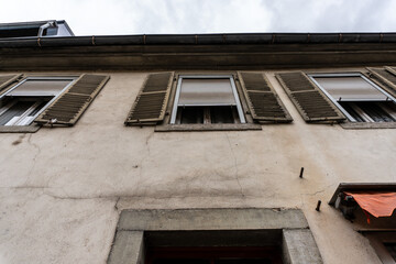 Looking up a a facade of an old house with window shutters