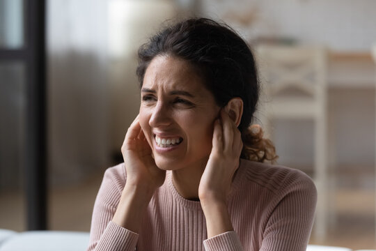 Be Quiet. Annoyed Nervous Latina Woman Suffer Of Loud Noise At Home Stick Fingers In Ears With Grimace On Face. Stressed Young Hispanic Lady Get Tinnitus Listen To Rumbling Music From Neighboring Flat