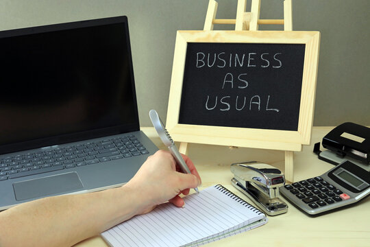 An Office Worker Carrying Out Office Duties And A Chalkboard With The Words Business As Usual