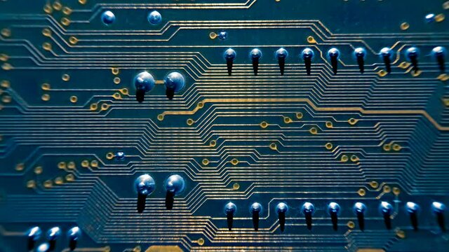 Golden colors metallic conductors on a printed circuit board along which a beam of light moves. Macro. Closeup