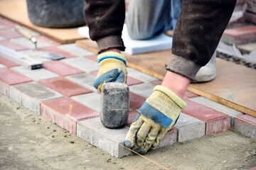 Builder laying of paving slabs on sand foundation base