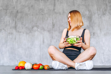 A sporty woman in sportswear is sitting on the floor with healthy food.