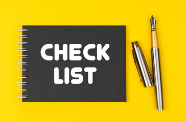 On a yellow background lies a pen and a black notebook with the inscription - Check List