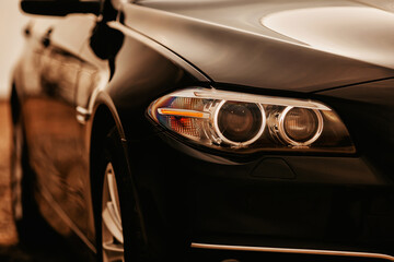 Obraz na płótnie Canvas Headlight of modern prestigious black car close up. Close up photo of modern car, detail of headlight.