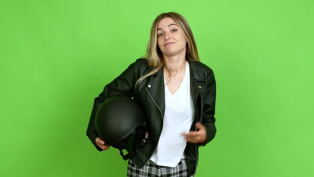 Young woman holding a motorcycle helmet having doubts over isolated background on green screen chroma key