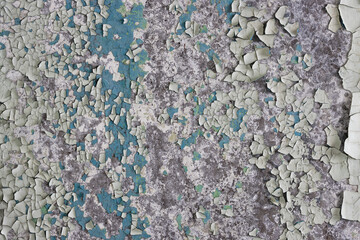 Peeling paint on the wall. Old concrete wall with cracked flaking paint. Weathered rough painted surface with patterns of cracks and peeling. Grunge texture for background and design. High resolution.