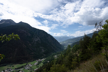 View of the valley from Doues, Valpelline. Mountains, trees, cloudy sky. Villages in the distance.