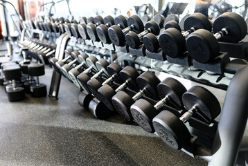 Naklejka na ściany i meble Set of metal dumbbells. Closeup many dumbbell on rack in sport fitness center. Gym equipment concept