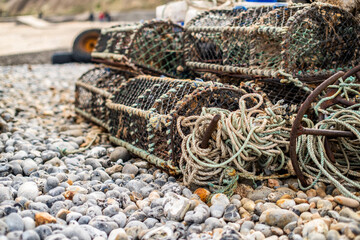 Crab fishing gear left on Cromer beach comprising fishing pots, rope, metal anchor and fenders. Shallow depth of field, selective focus and bokeh