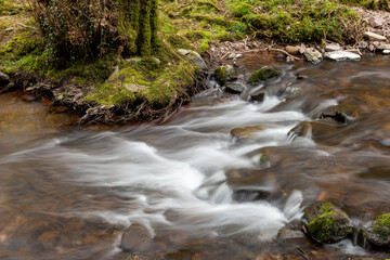 Naklejka na ściany i meble Long exposure of the Horner Water river flowing through Horner woods in Somerset