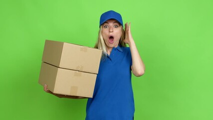 Young woman holding boxes for delivery with surprise and shocked facial expression over isolated background on green screen chroma key