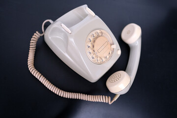 vintage white telephone set with retro style dialing dial on black background, concept of old...