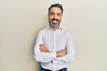 Middle age man with beard and grey hair wearing casual white shirt happy face smiling with crossed...