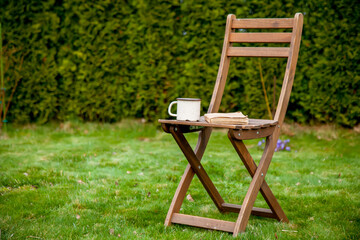 Old book with cup of tea on a table on green grass in spring