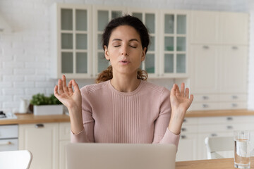 Home office yoga. Calm millennial hispanic female freelancer sit by pc with closed eyes breath deep...