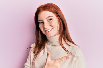 Young red head girl wearing turtleneck sweater smiling cheerful pointing with hand and finger up to the side