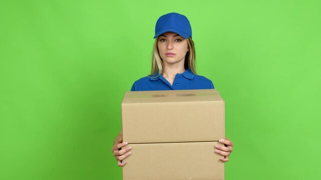 Young woman holding boxes for delivery looking side over isolated background on green screen chroma key