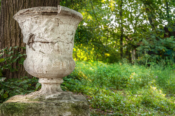 decorative stone vase on a pedestal in an old abandoned park