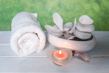 beautiful pink magnolia flower, smooth white stones in a stack, candles, white towel, concept of wellness spa treatments for the beauty of body and soul, massage, zen stone in the pool of serenity