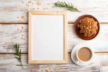 White wooden frame mockup with cup of coffee and cake on white wooden background. top view
